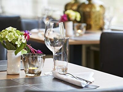 Een sfeervolle restauranttafel met wijnglazen en een kleurrijk boeket bloemen voor een gezellige ambiance.